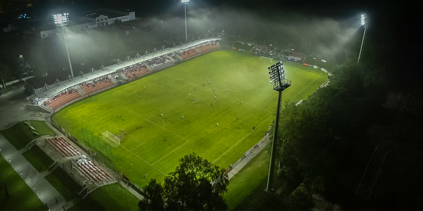 Zadaszona trybuna główna stadionu w Słupsku widziana z perspektywy murawy